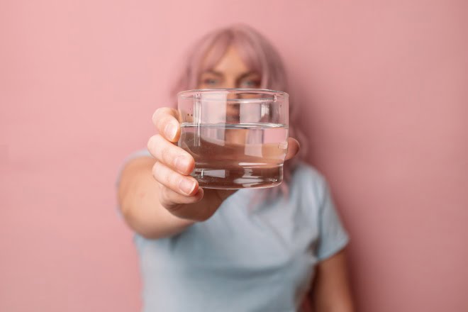 kobieta ze szklanką wody nawodnienie a ból głowy